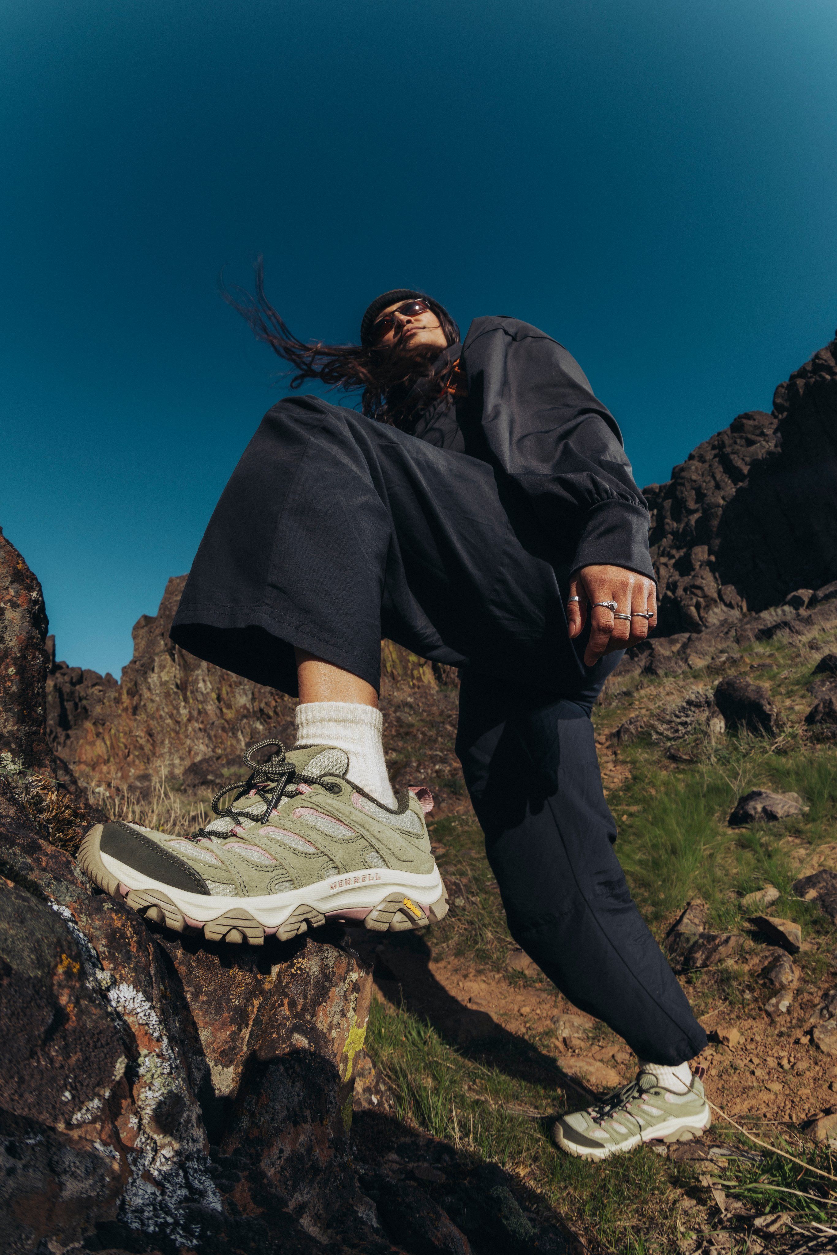 A woman wearing Merrell hiking shoes on a rocky trail.